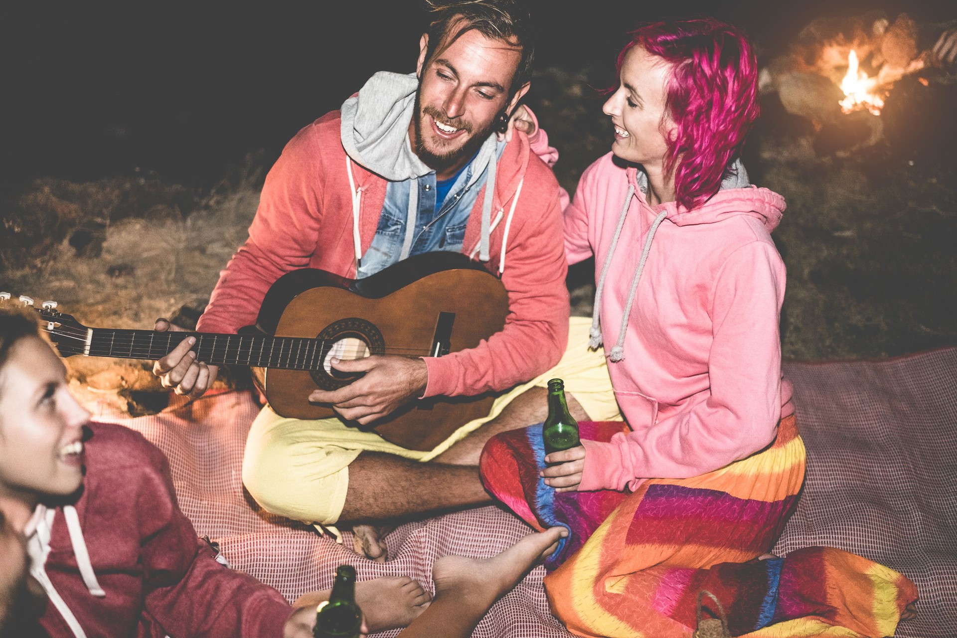 Trendy amis jouer de la guitare et boire de la bière prochain feu de plein air - gens heureux s’amuser camping en vacances vacances - Focus sur le visage de l’homme - amitié, fête et nature concept - filtre de contraste