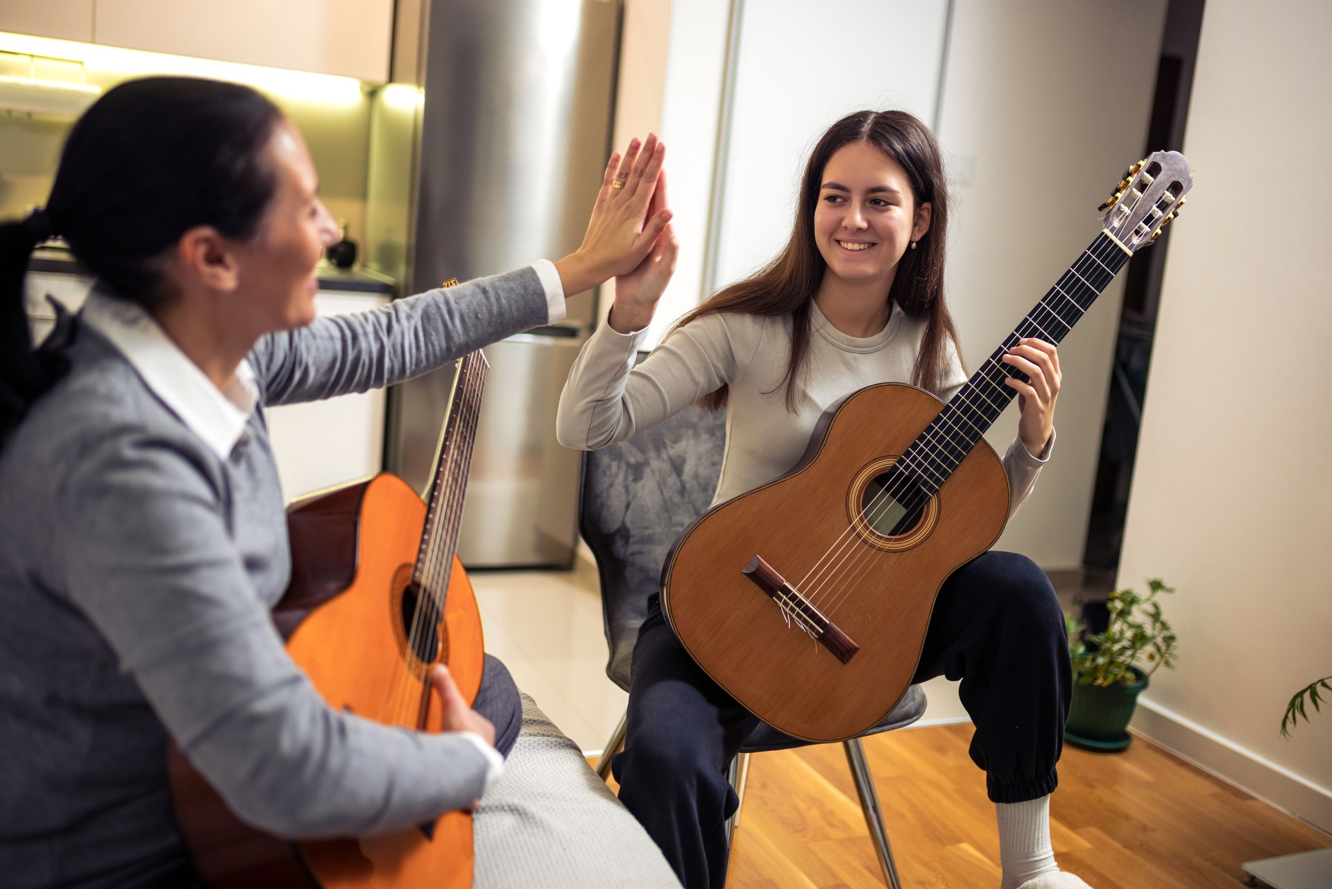 Mother and daughter playing guitar at home. A mother teaches her daughter to play the guitar.